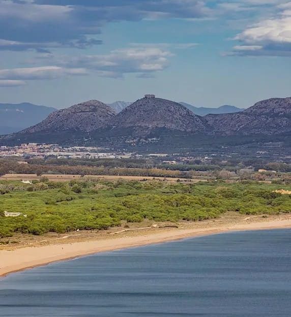 Вид на пляж и побережье с горными цепями на горизонте.