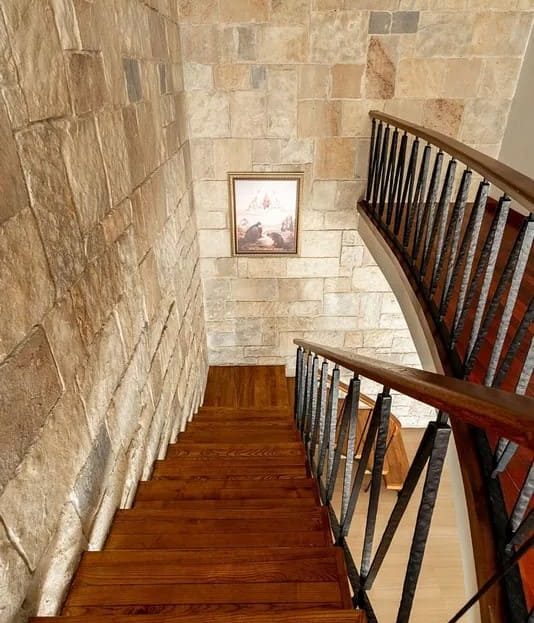 Дизайнерская лестница с каменной стеной в доме