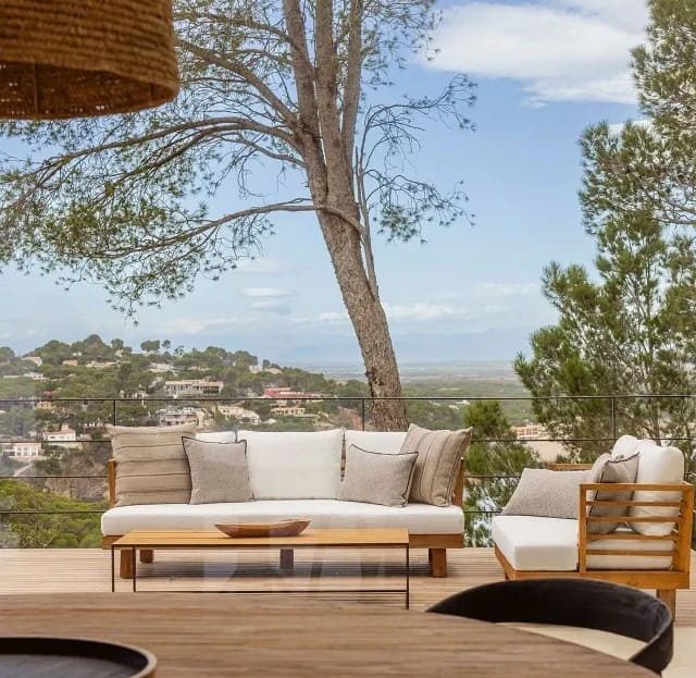 Уличная терраса с мебелью и видом на холмы и море.