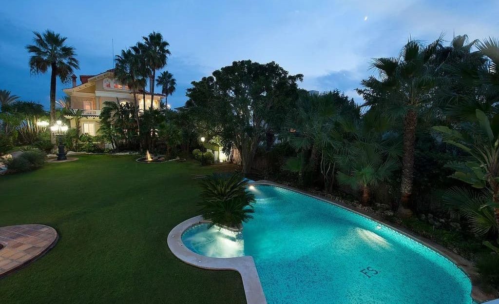 Бассейн и тропический сад виллы с вечерним освещением