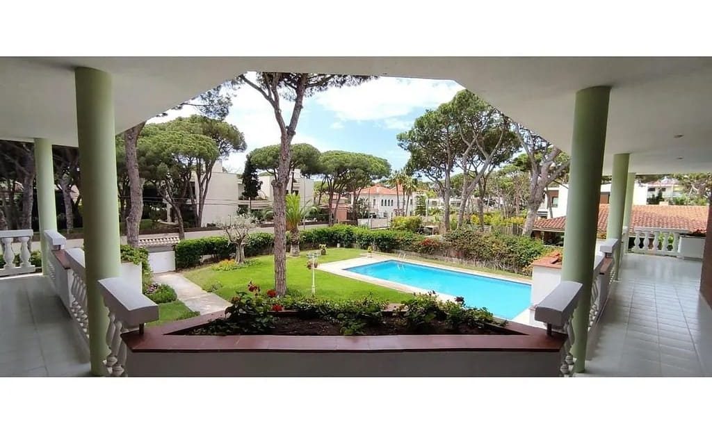 Крытая терраса с видом на сад и бассейн.