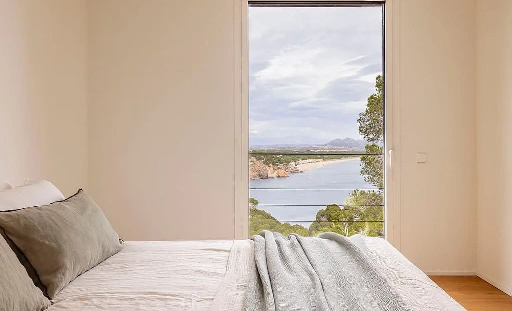 Вторая спальня с видом на море через большое окно.