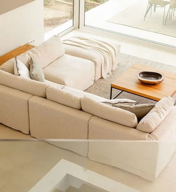 Угловая гостиная зона с большими окнами и видом на террасу и природу.