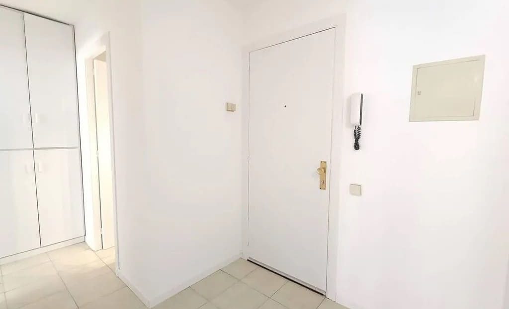 Прихожая квартиры с белыми стенами, входной дверью и встроенным шкафом.