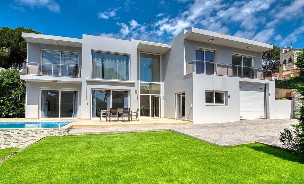Фасад современной виллы с зелёным садом и бассейном в Калонже