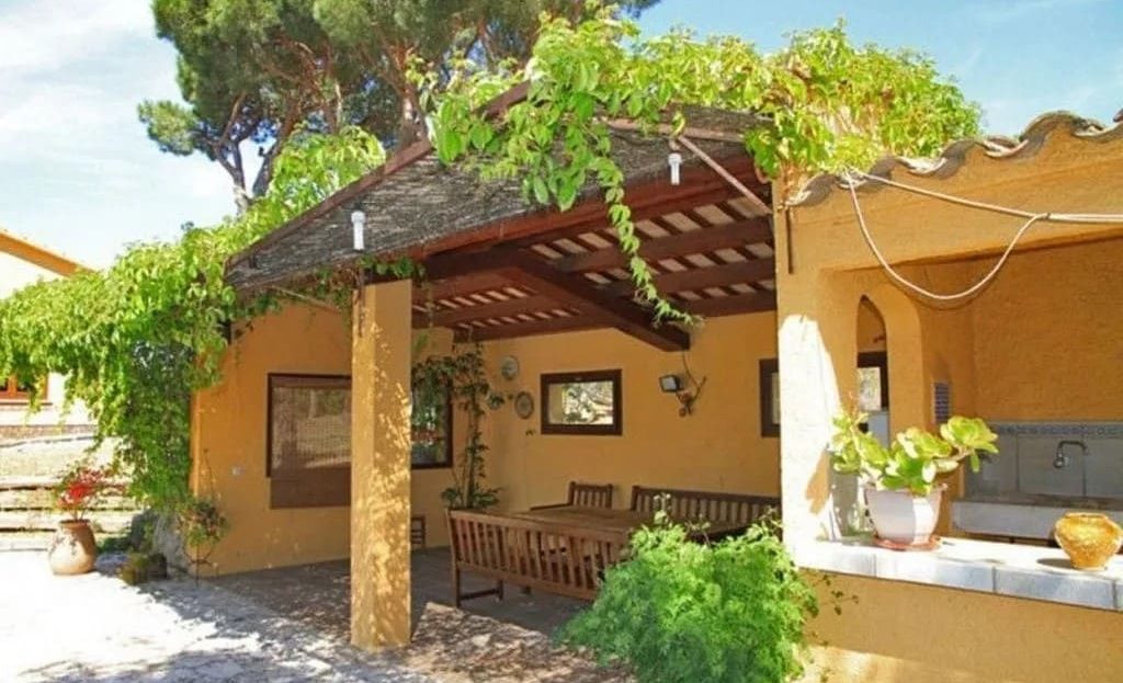 Фасад виллы с крыльцом и садом.