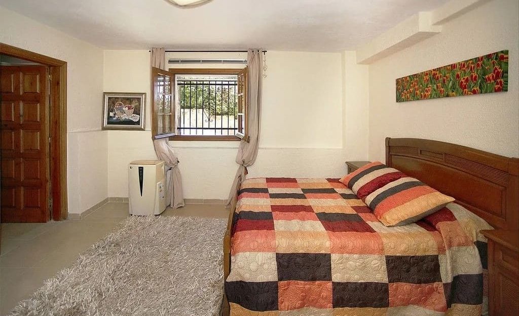 Спальня на нижнем этаже с большим окном и зоной отдыха.