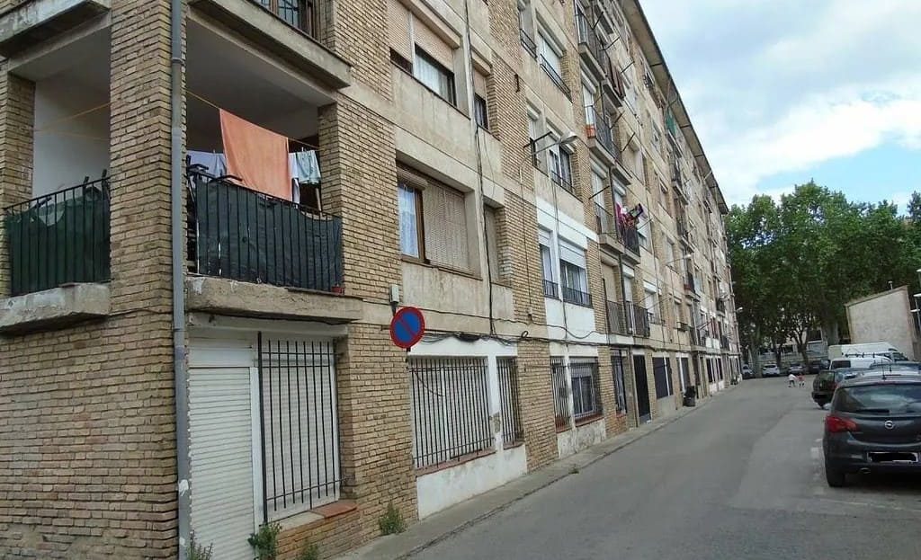 Фасад кирпичного многоквартирного дома на узкой жилой улице в районе El Sucre–Universitat.