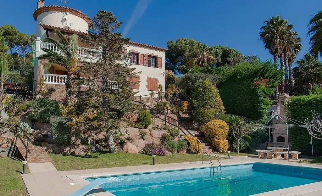 Фасад виллы с бассейном и садом.