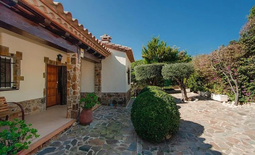 Главный вход в виллу с садом и мощёной площадкой.