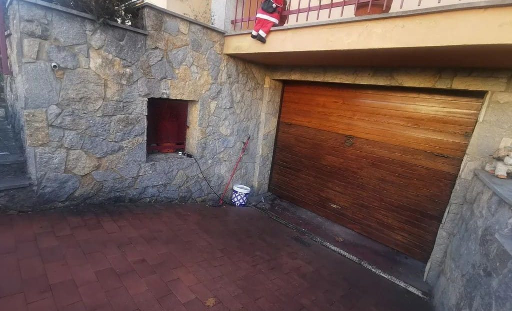 Подъезд к гаражу с каменной отделкой и деревянными воротами.