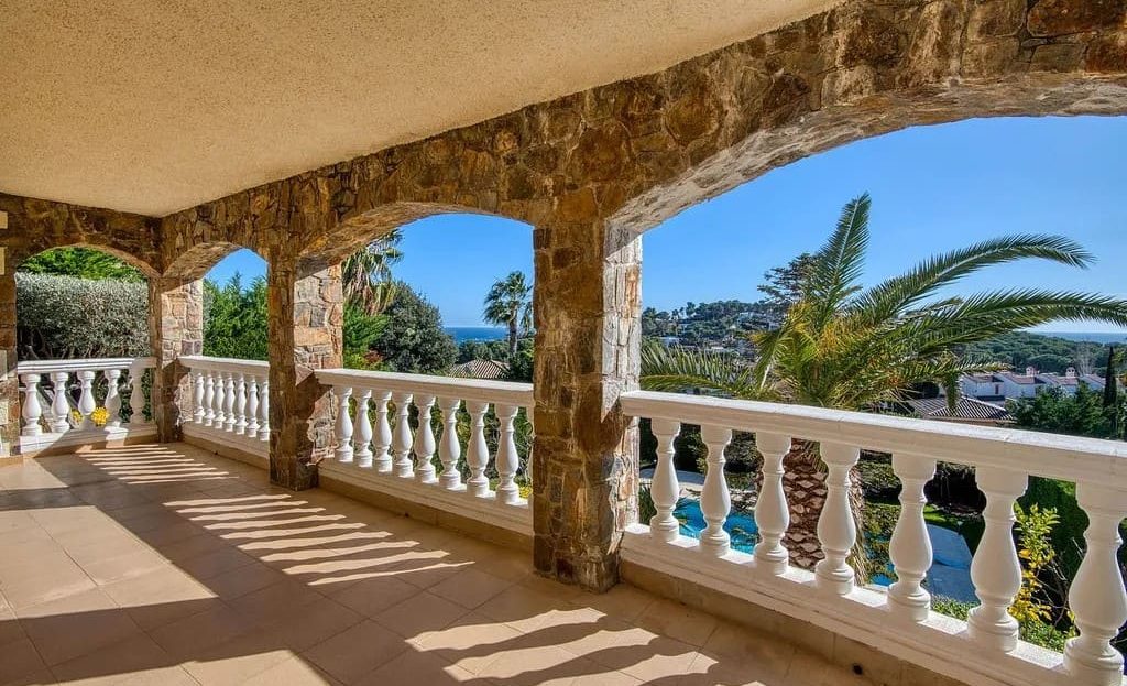 Крытая терраса с колоннами и видом на бассейн.