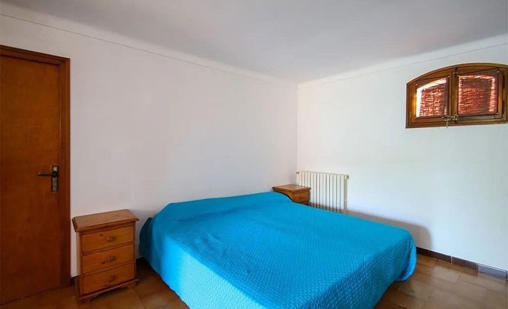 Спальня с двуспальной кроватью и деревянной мебелью.