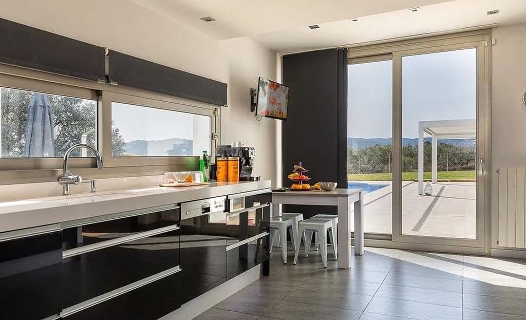 Современная кухня с большими окнами и видом на сад