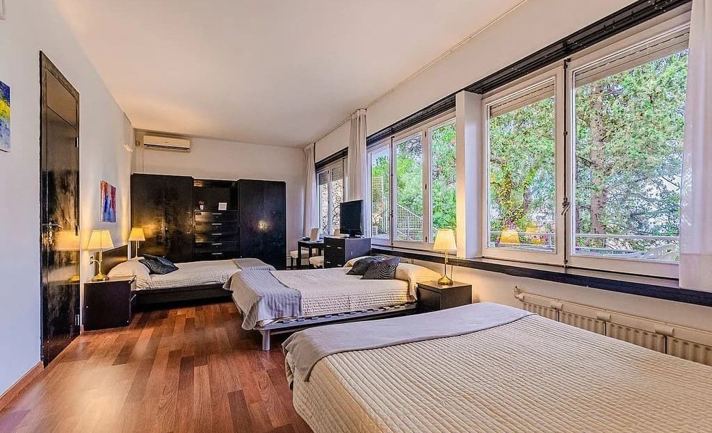 Спальня с большими окнами и видом на зелёную зону