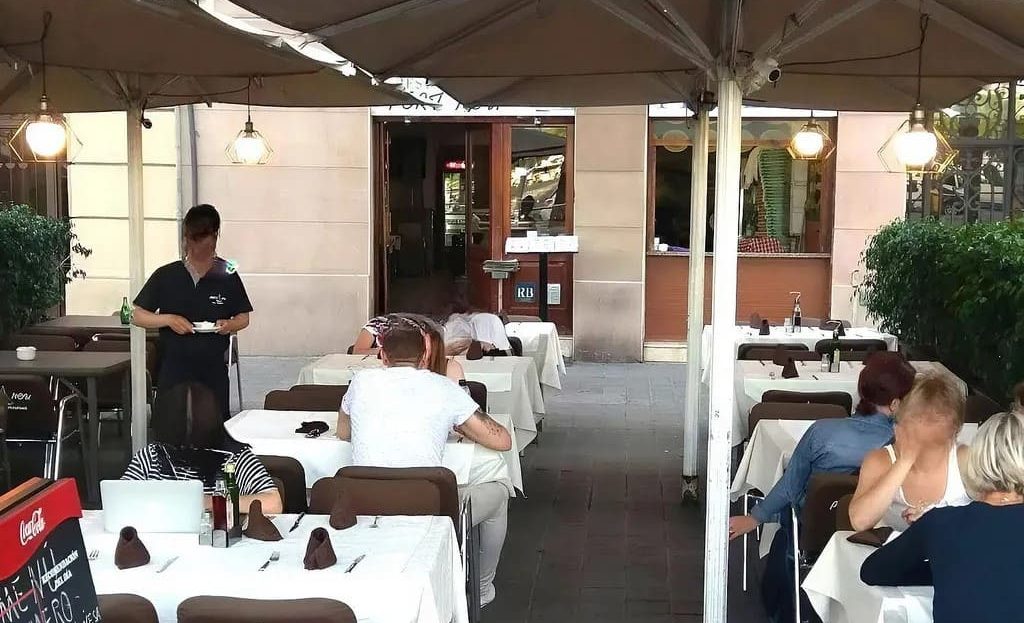 Летняя терраса ресторана в туристическом районе Сьютат Велья с посадочными столами для гостей.