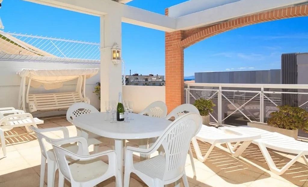 Терраса с обеденной зоной и лежаками в пентхаусе рядом с пляжем.