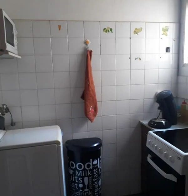 Кухонная зона с плитой, раковиной и бытовыми предметами.