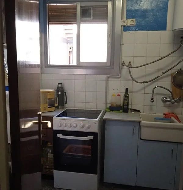 Отдельная кухня с окном, плитой и навесными шкафами.