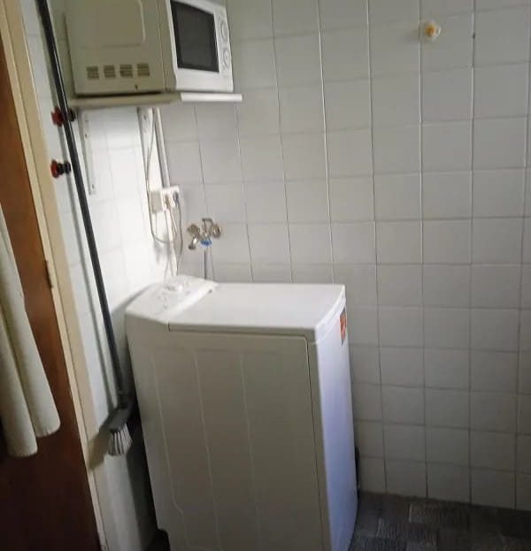 Пространство кухни с плиткой на стенах и установленной стиральной машиной.