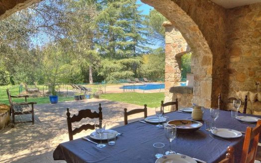 Летняя столовая под каменным арочным навесом с видом на сад усадьбы.