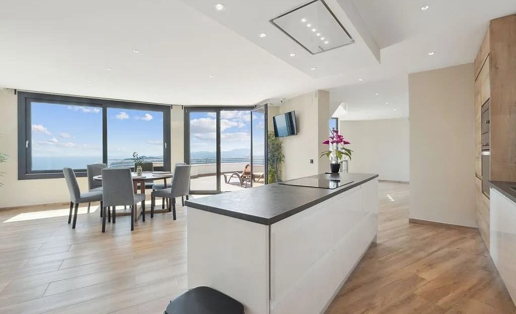 Кухня-столовая с островом и большими окнами.