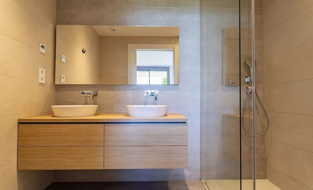 Современная ванная комната с душевой кабиной и деревянной мебелью.