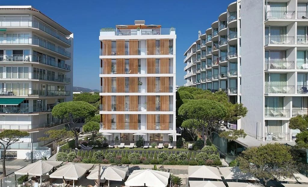 Фасад новостройки в Плая-де-Аро, вид с уровня улицы между соседними зданиями