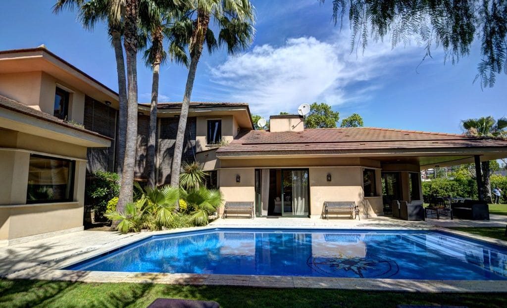 Вилла с большим бассейном и пальмами на ухоженном участке