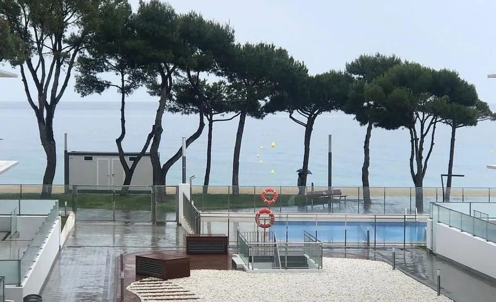 Зона бассейна и виды на море в новостройке Плайя-де-Аро, окружённой соснами