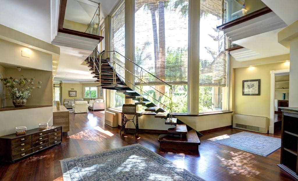 Просторный холл с панорамными окнами и дизайнерской лестницей