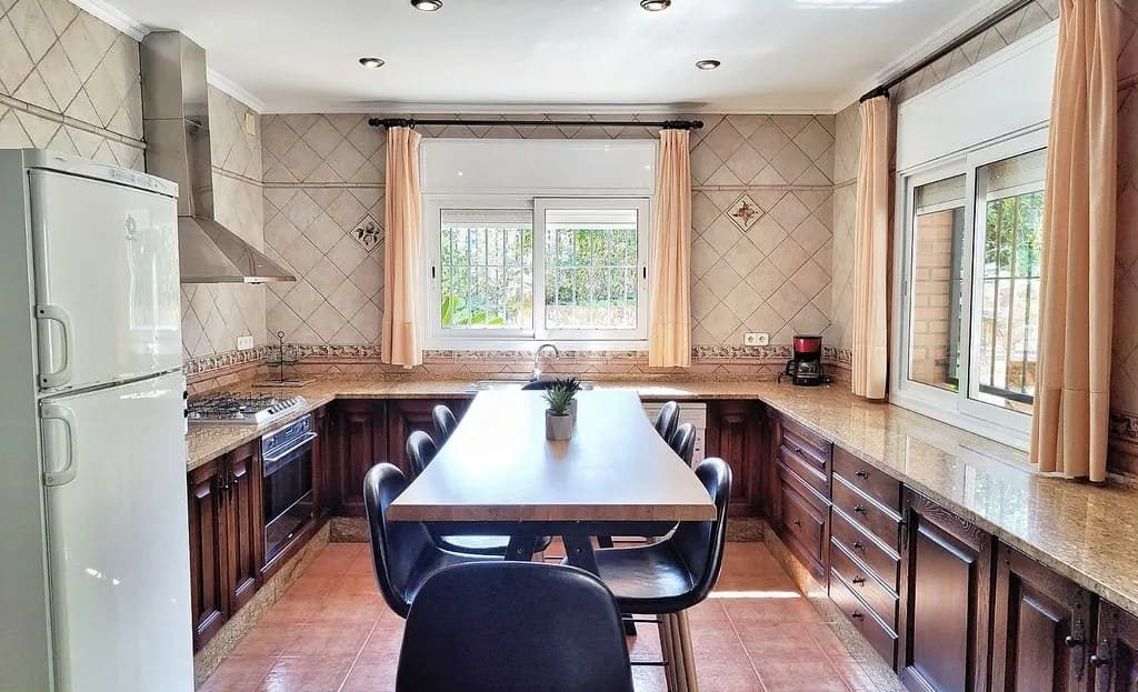 Большая кухня с длинным рабочим столом и окнами