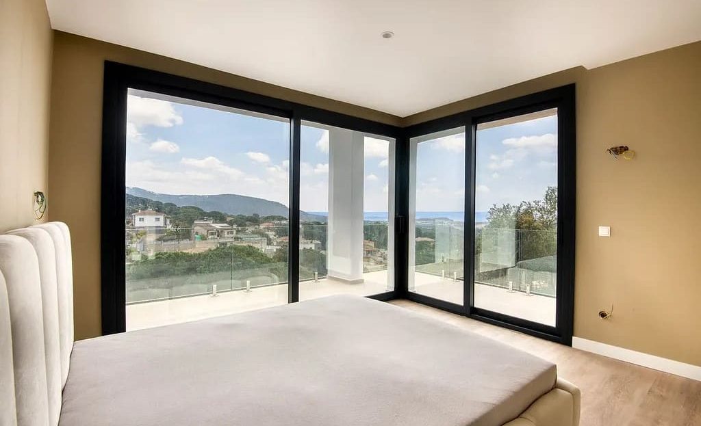 Спальня с панорамными окнами и видом на холмы.