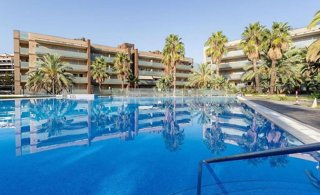 Бассейн жилого комплекса с пальмами и зонами отдыха