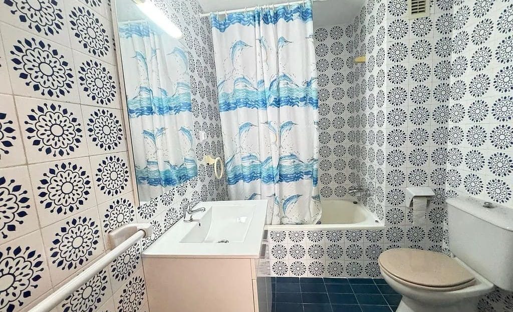 Ванная комната с ванной, раковиной и узорчатой плиткой на стенах.