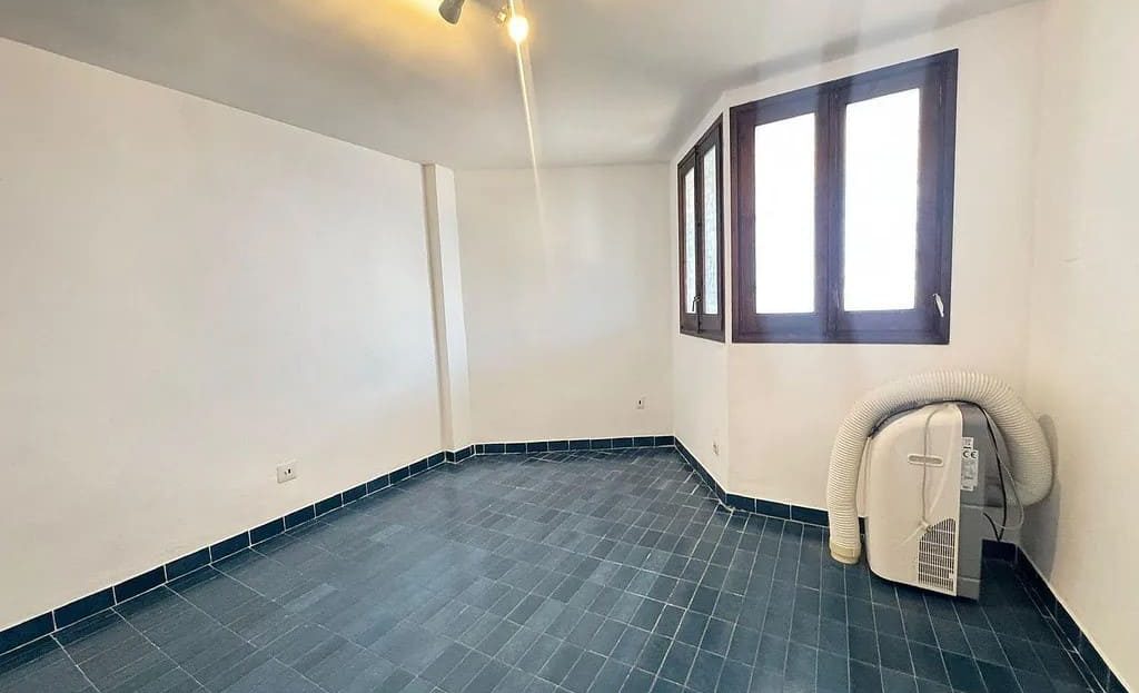 Светлая спальня с синим плиточным полом и окном.