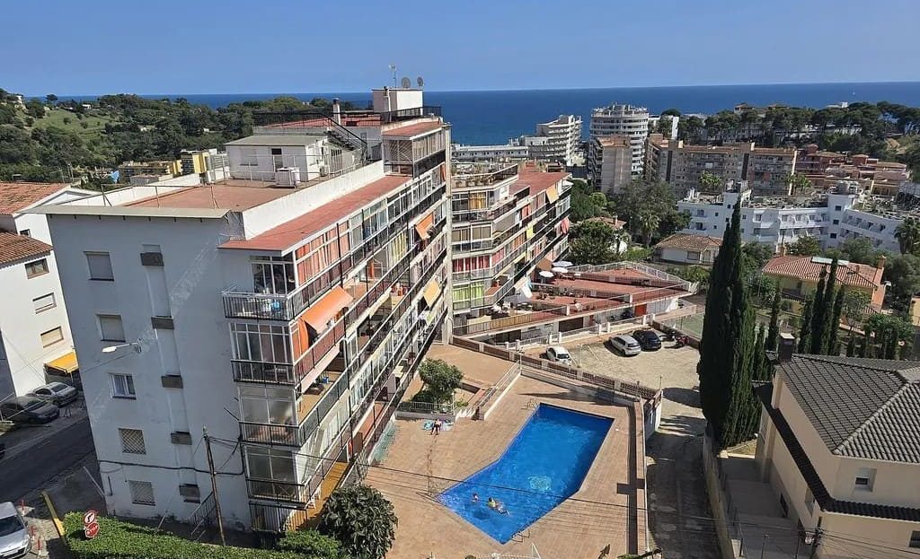 Панорамный вид на жилой комплекс с бассейном и море в Ллорет-де-Мар