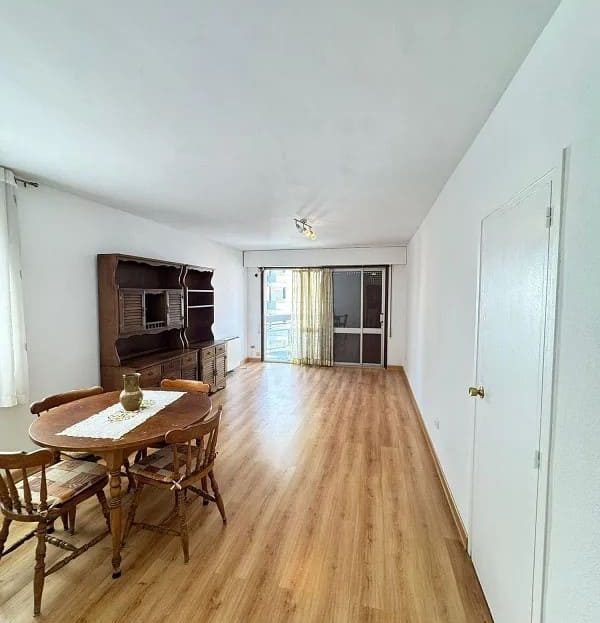 Просторная гостиная с большим окном и зоной столовой.