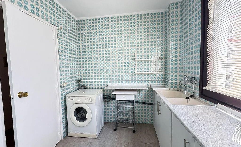 Кухня с мойкой, стиральной машиной и плиточной отделкой стен.