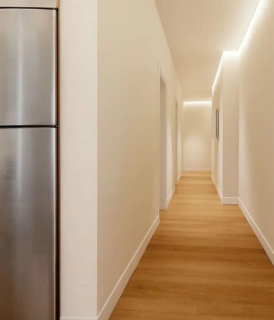 Коридор квартиры с новым напольным покрытием и встроенным освещением.