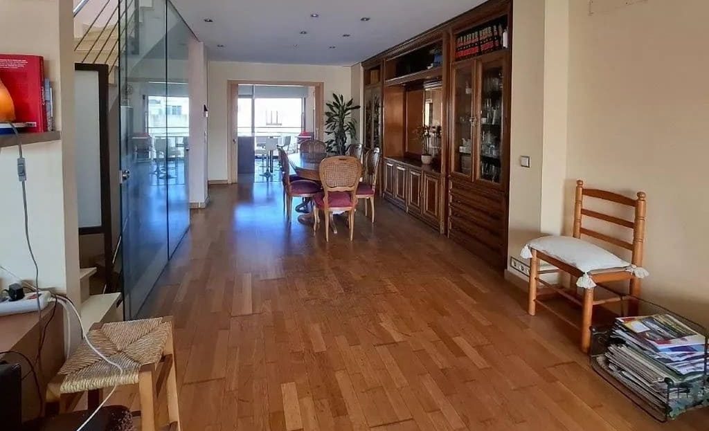 Гостиная с деревянным полом и встроенными шкафами, вид на зону столовой.