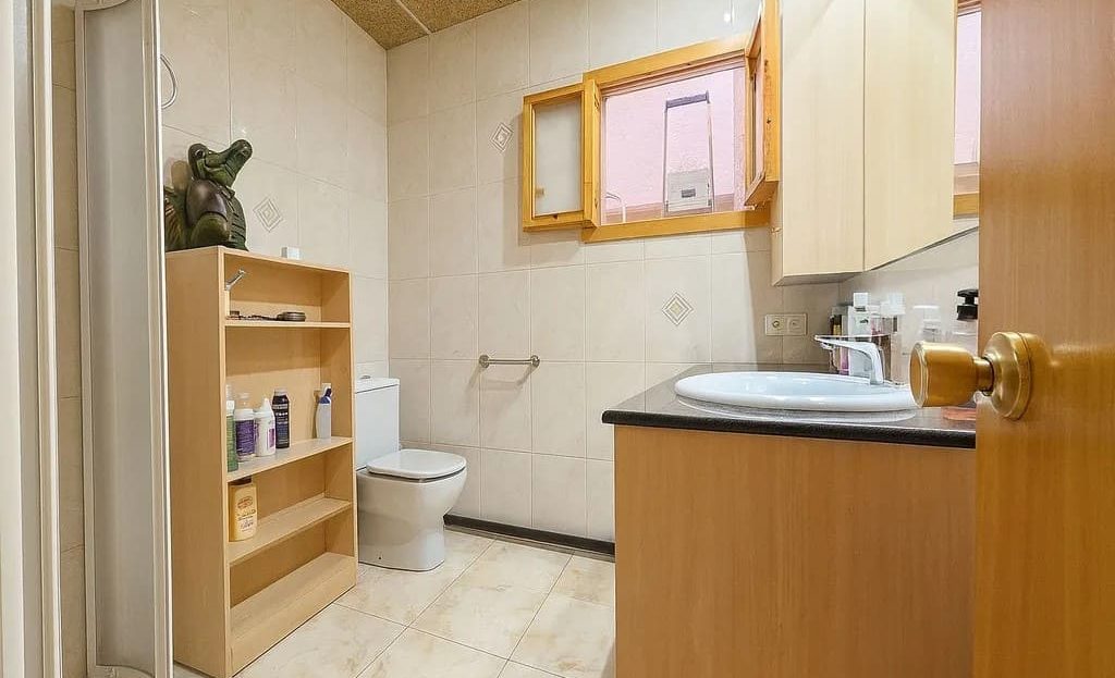 Санузел с душевой зоной и раковиной, рядом с кухонным пространством.