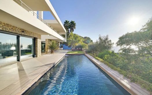 Длинный бассейн инфинити с видом на море и современной виллой