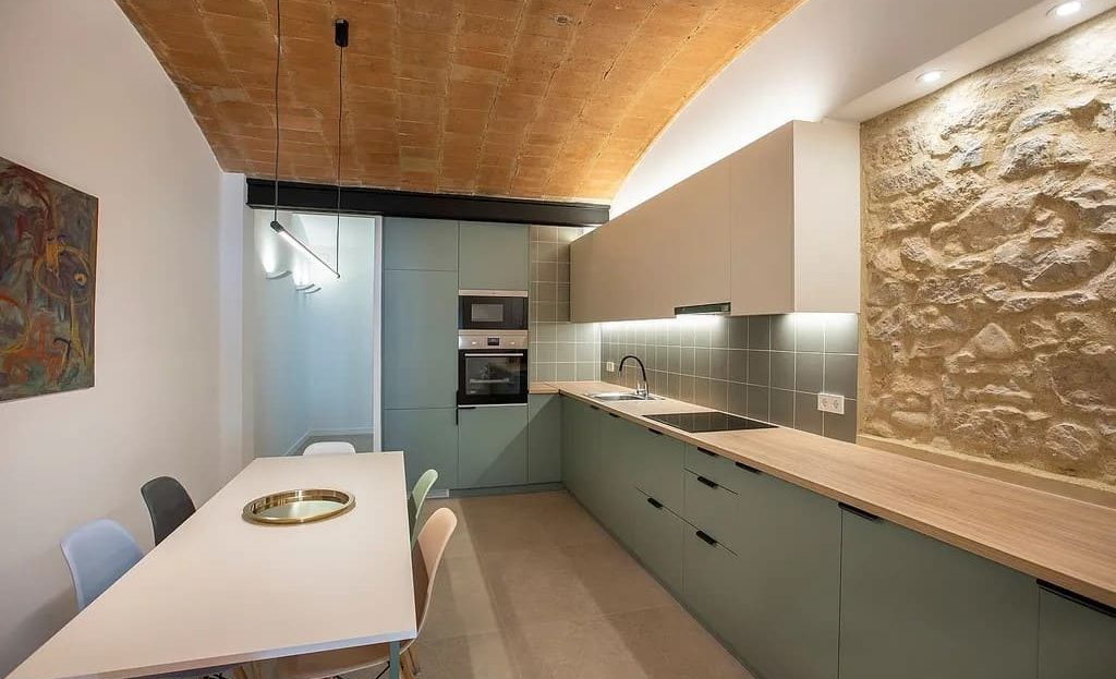 Кухня-менхадор с кирпичным сводчатым потолком и каменной стеной.