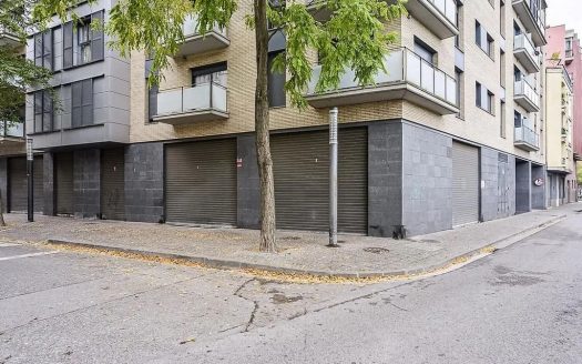 Фасад здания с закрытыми коммерческими помещениями и деревьями вдоль улицы