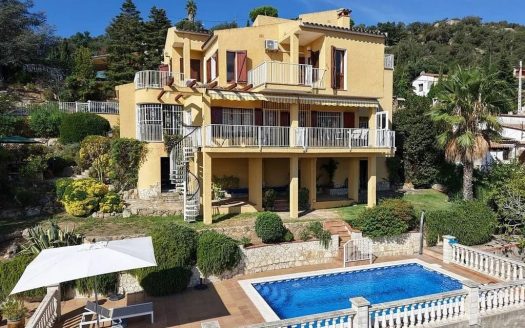 Фасад виллы с бассейном и садом.