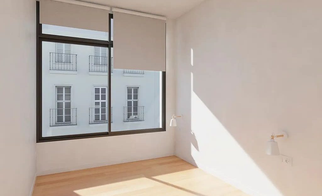 Светлая комната с большим окном и деревянным полом.