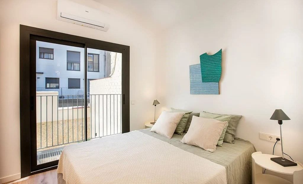 Спальня с большим окном, кондиционером и современной отделкой.