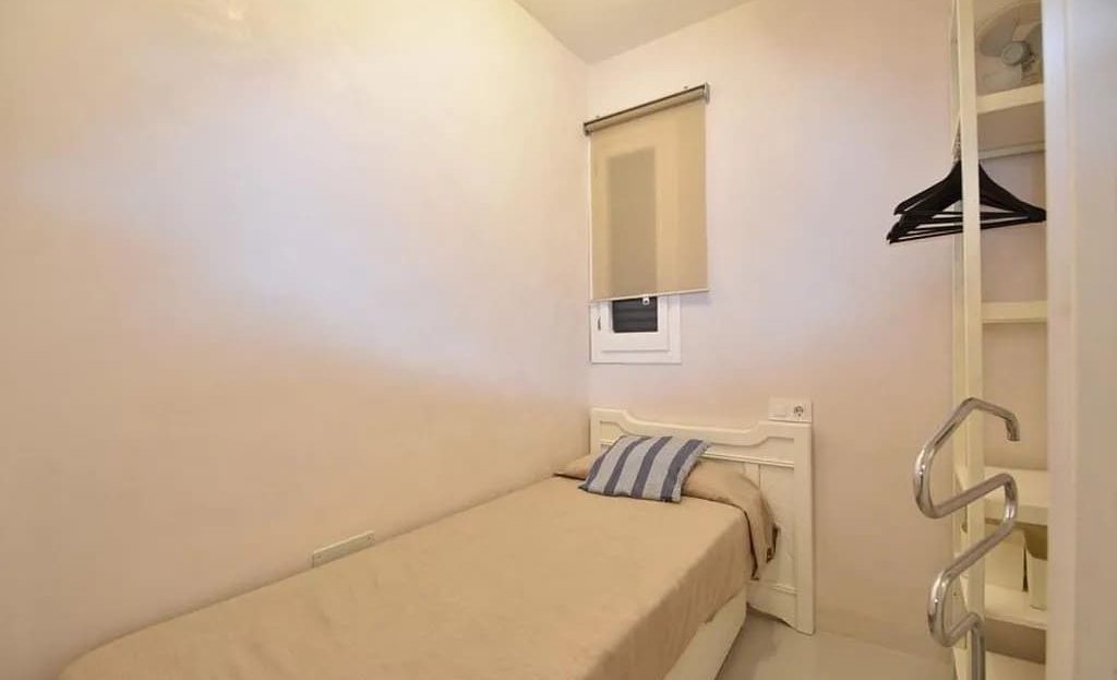 Небольшая спальня с односпальной кроватью и окном.