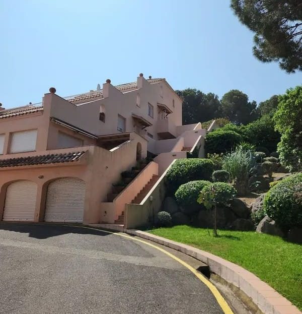 Фасад комплекса таунхаусов с зеленой зоной на склоне.